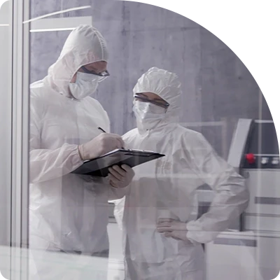Two workers in a state-of-the-art clean manufacturing facility review notes on an access-secured tablet.